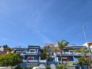 a blue building with palm trees in front of it at lagoon apartment 2 in Moulay Bousselham