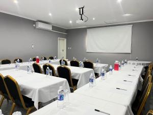 a conference room with white tables and chairs and a screen at Cumberland Guest Lodge in Bulawayo +18 photos