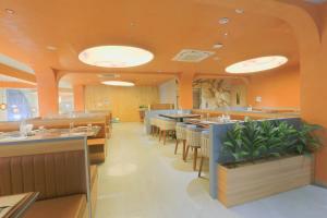 a restaurant with orange walls and tables and chairs at Hotel Nova Platinum Ujjain in Makoria Ām