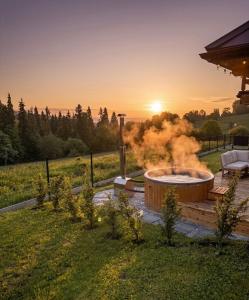 a hot tub in a yard with the sunset in the background at Domki pod Bachledówką in Czerwienne