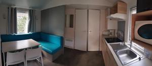 a small kitchen with a blue couch and a table at Camping 2 étoiles - Piscine - ccbfida in Vernet-les-Bains +8 photos