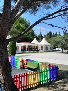 a colorful fence with a bench and a tree at Camping 3 étoiles - Piscine - ccbfii0 in Châteauneuf-de-Gadagne +18 photos