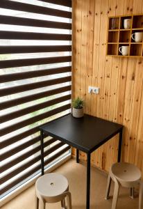 a black table and two stools in a room with wood at Pool Hause Palanga in Palanga