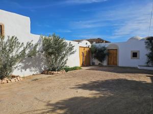 a white building with a wooden door in a yard at Dar Chauphaly in Houmt Souk