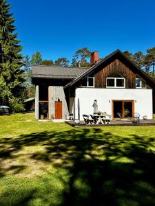 a white house with a black roof and a yard at Atpūtas vieta Brāļtīrumi in Pūrciems