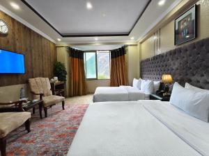 a hotel room with two beds and a flat screen tv at Millennium Inn Hotel Naran in Naran +40 photos