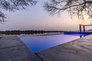 a pool of blue water next to a lake at Boteti Tented Safari Lodge in Maun
