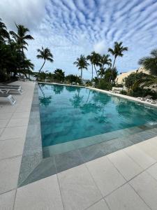 a swimming pool with blue water and palm trees at Sunset Paradise in Baie Nettle