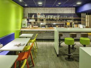 a restaurant with green walls and tables and chairs at ibis budget Parauapebas in Parauapebas