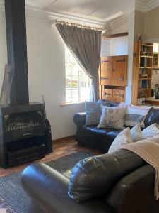 a living room with a leather couch and a fireplace at God's Gift Cottages in Clarens