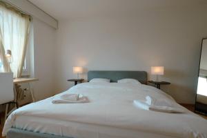 a bedroom with a large white bed with two white towels at Cozy Apartment with Easy Access to Bern in Bern +2 photos