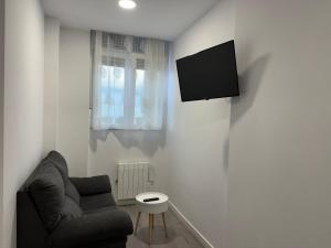 a living room with a couch and a tv on a wall at GRUPOELE3 MUXIA PUERTO in Muxia