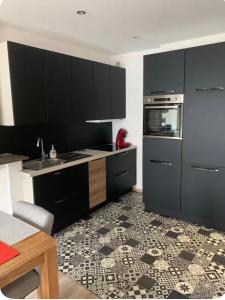 a kitchen with black cabinets and a tile floor at Le clocher d Ardres in Ardres