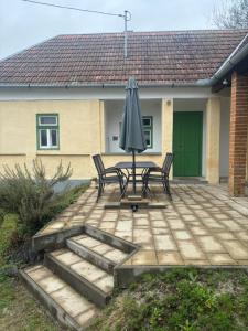 a patio with a table and an umbrella in front of a house at Sárga-part Vendégház in Cserépváralja