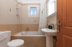 a bathroom with a toilet and a sink and a bath tub at The old inn in Laganas +22 photos