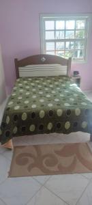 a bed with a polka dot bedspread and a window at Casa Nascer do Sol in Sangão