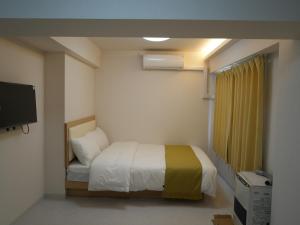 a small bedroom with a bed and a television at attomi hostel 2 in Sapporo