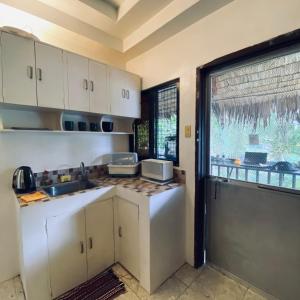 a kitchen with white cabinets and a sink and a window at Duck & Drift - a Sleeper Hostel - Just 1,7km from Airport in Puerto Princesa City