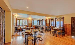 a restaurant with tables and chairs and windows at Hotel Monal Inn, Pangot Wildlife and Bird Sanctuary in Nainital