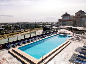 a swimming pool on the roof of a building with chairs at River Palace Hotel in Atyrau