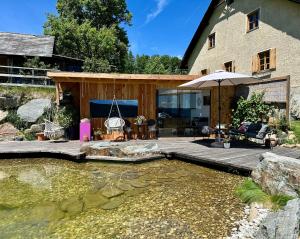 a backyard with a pond and a house with an umbrella at Mauthnerhube Ferienwohnung mit Sauna, Whirlpool, Hüttenfeeling in Sankt Oswald ob Eibiswald