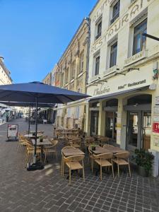 an outdoor cafe with tables and chairs and an umbrella at Hôtel Restaurant L'Industrie in Saint-Omer