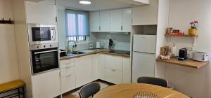 a kitchen with white cabinets and a table with chairs at Casa dos Azevedos in Câmara de Lobos
