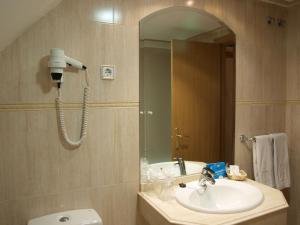 y baño con lavabo, espejo y aseo. en Hotel Don Luis en Madrid