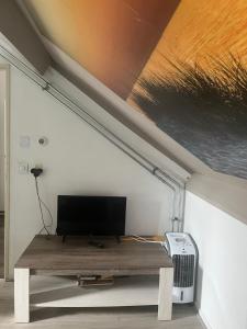 a living room with a table with a tv on it at Studio vlak bij het strand in Petten