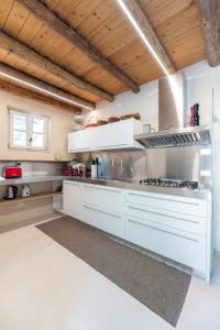 a large kitchen with white appliances and wooden ceilings at Agriturismo Monte Bisson - Piscina Privata in Soave +27 photos