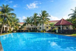a large swimming pool in front of a building with palm trees at Solrise Villa in Palmar