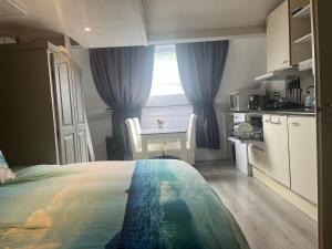 a bedroom with a bed and a table and a kitchen at Studio vlak bij het strand in Petten