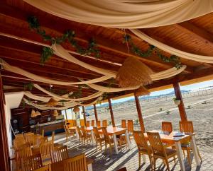 a group of tables and chairs under a wooden roof at OLIVE Home in Durrës