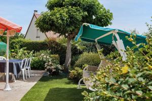 a garden with a table and a green umbrella at chambre d'hôtes des bleuets in Saint-Firmin-des-Prés
