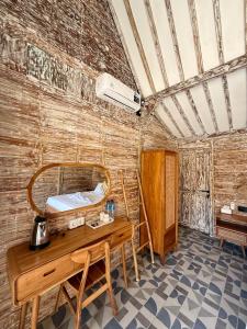 a room with a wooden desk and a bed at ADIBA village in Gili Meno