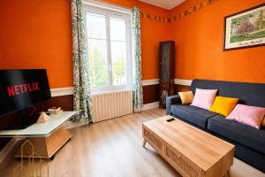 a living room with orange walls and a blue couch at L'Esprit Descartes in Roanne
