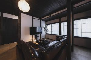 a living room with a leather couch and a tv at Hidasumika Ojin AN in Takayama