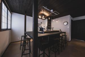 a kitchen with a bar with stools in a room at Hidasumika Ojin AN in Takayama