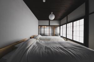 two beds in a room with two windows at Hidasumika Ojin AN in Takayama