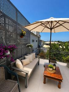 a patio with a couch and an umbrella on a balcony at Panagiotis' Seaside Apartment, Giorgos`House in Gialova