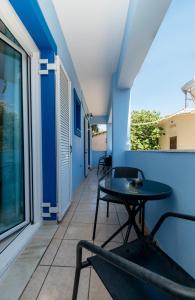 a table and chairs on a balcony with a blue wall at The old inn in Laganas