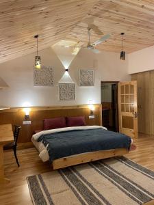 a bedroom with a large bed and a wooden ceiling at Kut House in Pālampur