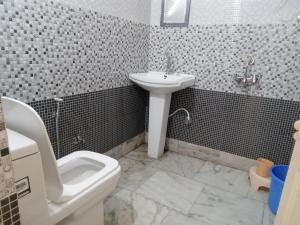 a bathroom with a white toilet and a sink at Swayambhu Hotel in Rudraprayāg