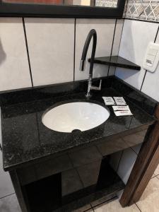 a sink in a bathroom with a black counter at Pousada das Águas in Piratuba +16 photos