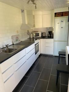 a kitchen with white cabinets and a sink and a refrigerator at Brygghuset between Hjo and Tidaholm in Hjo