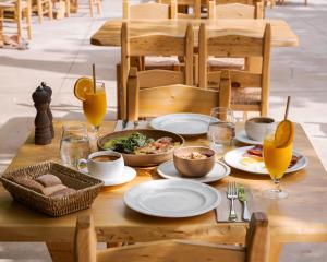 a wooden table with plates of food and glasses of orange juice at Manelis Mills Estate, Guest Houses & Restaurant in Plakias