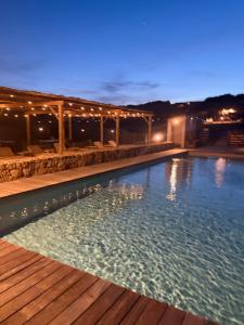 a large swimming pool at night with a wooden deck at A Santa Trinita in Bonifacio