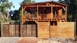 a wooden house with a deck on top of a fence at Encantos del Monte in Gobernador Roca