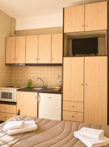 a kitchen with wooden cabinets and a bed with towels at PNOÉ rooms in Ilia