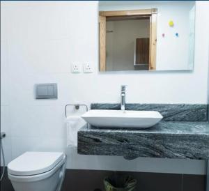 a bathroom with a sink and a toilet and a mirror at SPAR Serviced Apartments- سيبار للشقق المخدومة in Al Hofuf